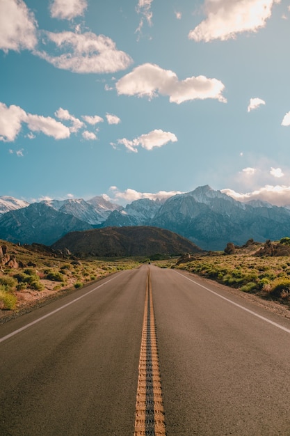 Free photo vertical shot of a road with the magnificent mountains under the blue sky captured in california