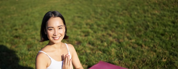 Free Photo vertical shot of young asian woman doing yoga practice mindfulness smiling and looking relaxed