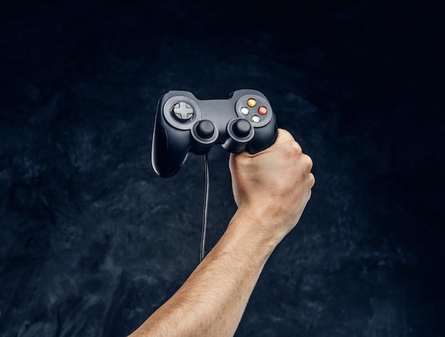 Foto gratuita controller per console per videogiochi in mano al giocatore sullo sfondo del muro scuro