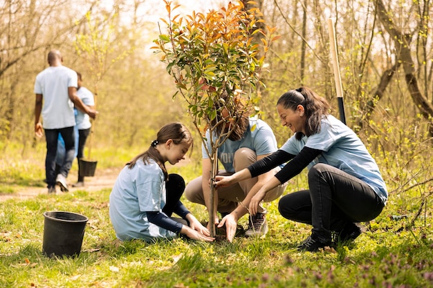 Free photo volunteers and a little kid planting tree and covering hole in the ground