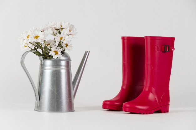 Free photo water boots next to a watering can with flowers
