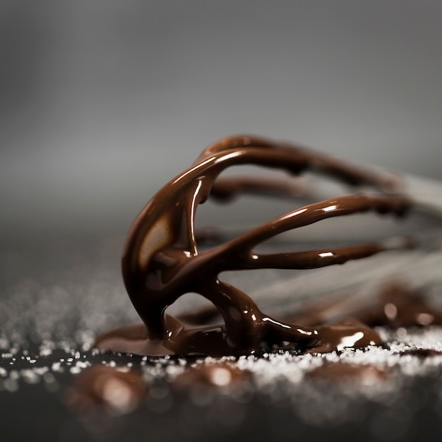 Free photo whisk filled with melted chocolate close-up