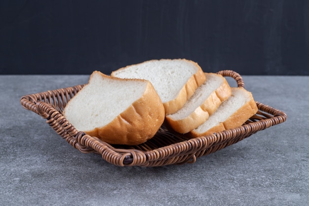 Foto gratuita cesto di vimini di fette di pane bianco posto sul tavolo di pietra.