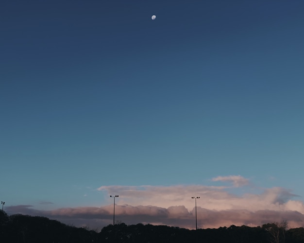 Free Photo wide shot of a half moon at the sky over the gray clouds