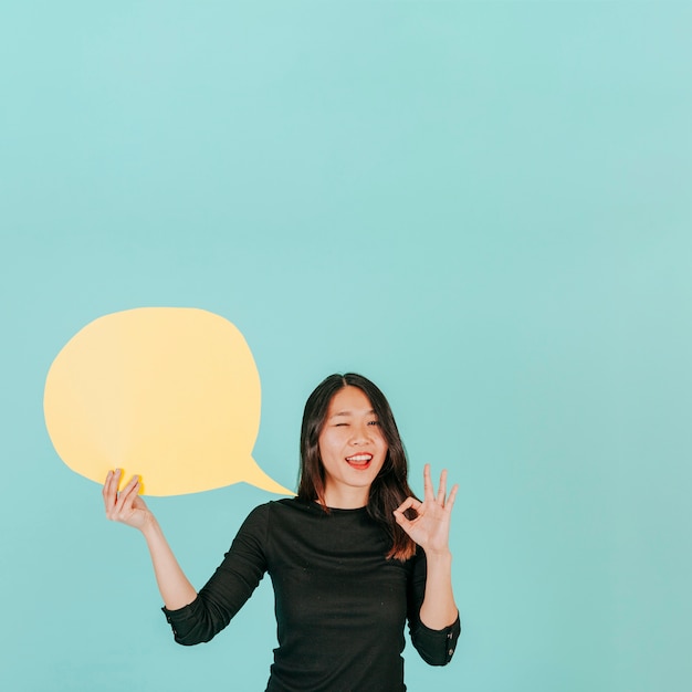 Free Photo winking woman with speech bubble gesturing ok