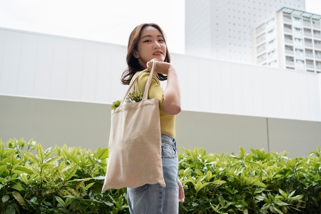 Foto gratuita donna che trasporta generi alimentari nel colpo medio della borsa di tote