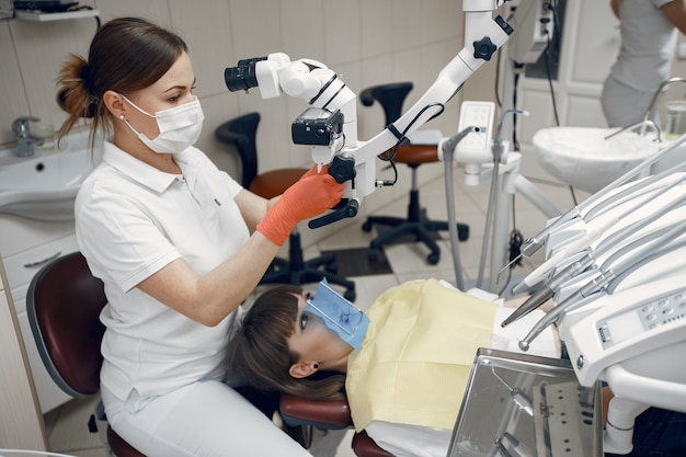 Foto gratuita donna presso l'ufficio del dentista. il medico conduce un esame. la ragazza tratta i suoi denti