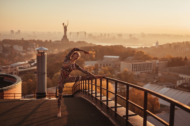 Free Photo woman doing yoga on the roof of a skyscraper in big city