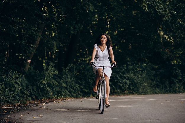 Free photo woman in dress riding bicycle in park