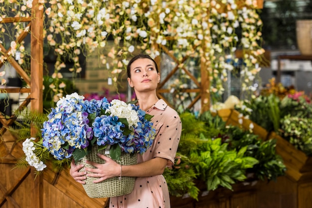 Free photo woman holding pot with flowers in green house