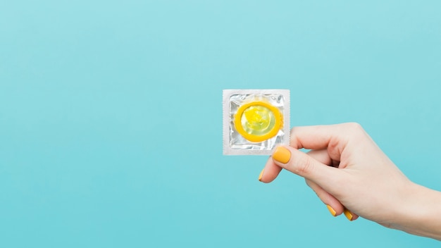 Free photo woman holding up a yellow condom