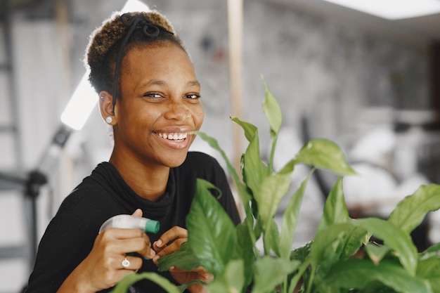 Free photo woman at home. girl in a black sweater. african woman at the office. person with flowerpot.