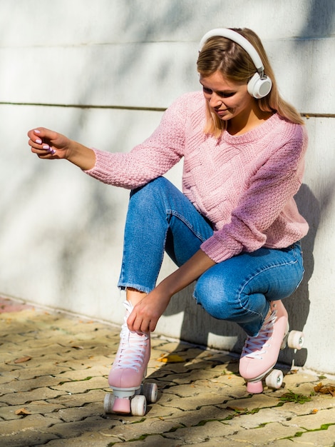 Woman in jeans with roller skates and headphones