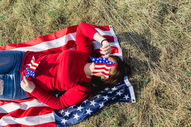 Woman lying on fabric of American flag on field