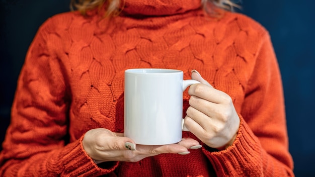 Free Photo woman in orange sweater holding a white cup with both hands,