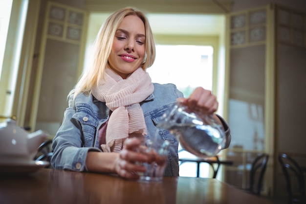 Free photo woman pouring water from jug into glass