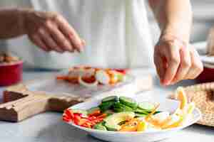 Free photo woman preparing spring rolls in rice paper on kitchen table