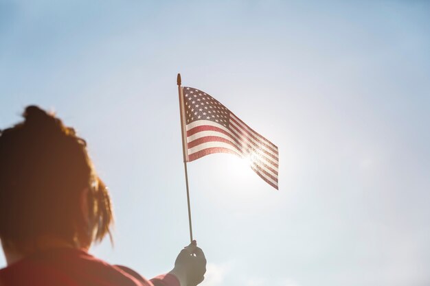 Woman raising American flag to bright sun