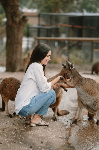 Woman in the reserve is playing with a kangaroo