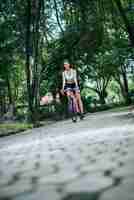 Free photo woman riding a road bike in the park. portrait of young beautiful woman on pink bike.