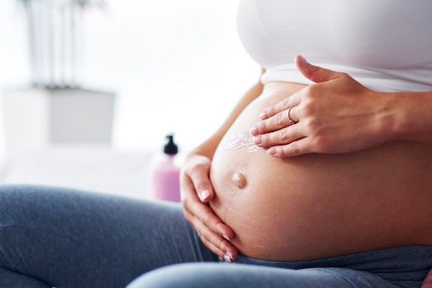 Free photo woman's hand applying moisturizer her belly