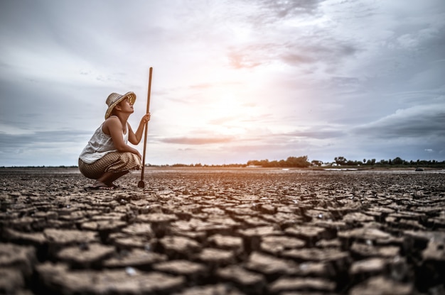 Foto gratuita la donna sedette la mano e prese un siem su terreno asciutto e guardò il cielo.