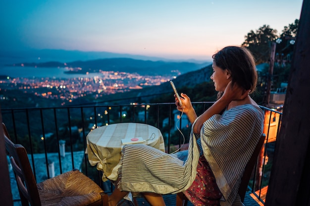 Free Photo woman sits on the balcony, in the background the night city