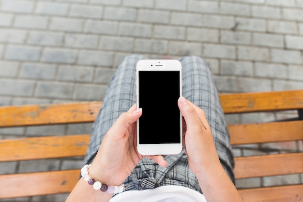 Free photo woman sitting on bench using cellphone