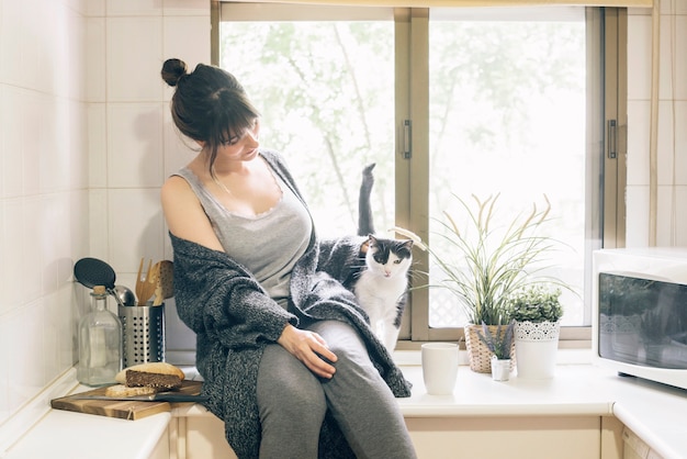 무료 사진 여자가 그녀의 고양이와 부엌에 앉아
