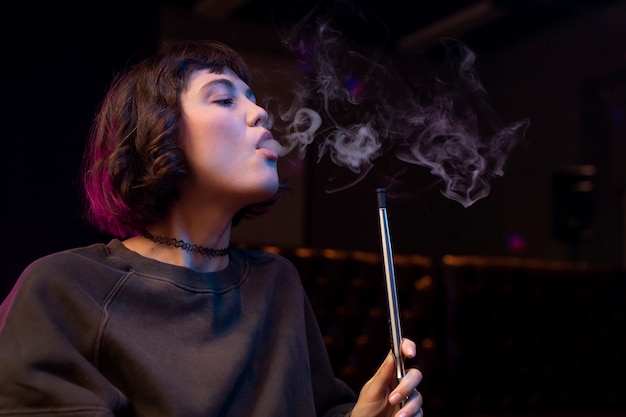 Free Photo woman vaping from a hookah indoors