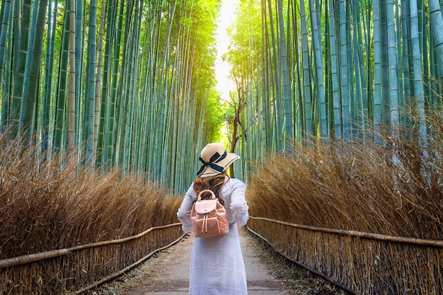 Free photo woman walking at bamboo forest in kyoto, japan.