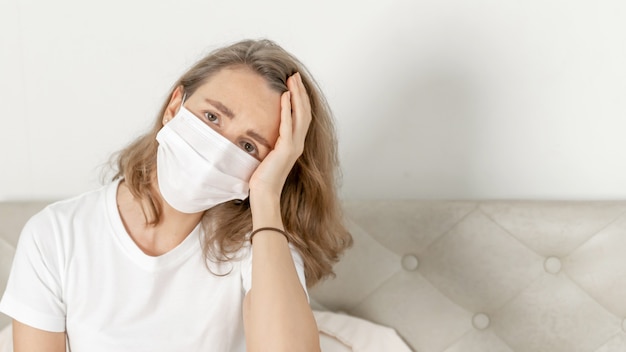 Foto gratuita donna che indossa una maschera per proteggere la sensazione di mal di testa e tosse a causa del coronavirus covid-19 nella stanza di quarantena