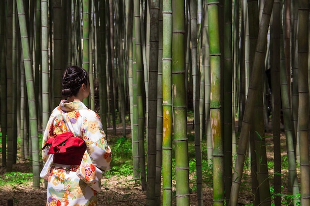 Free photo woman wearing japanese traditional kimono garment and standing in a bamboo forest