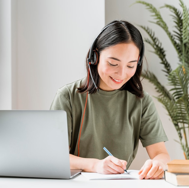 Free Photo woman with headset having video call on laptop