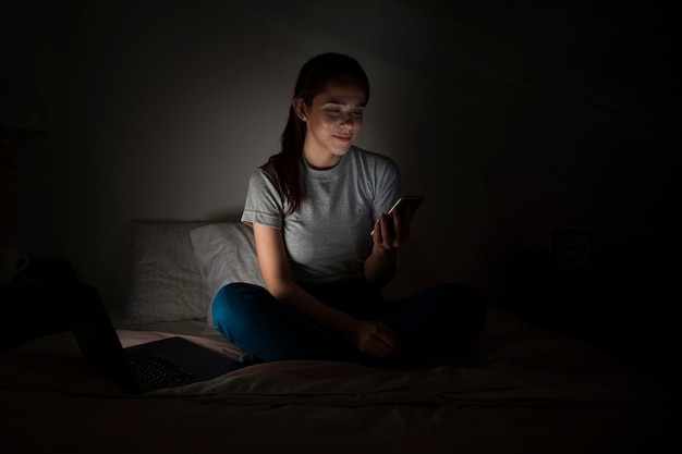 Woman working on smartphone late at home