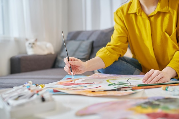 Free Photo a woman in yellow shirt painting and looking involved