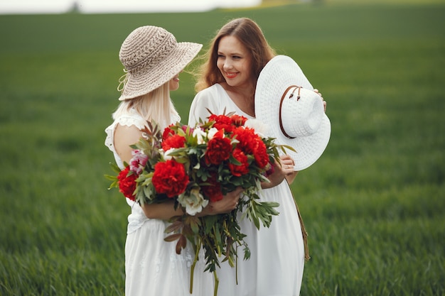 Free photo women in elegant dress standing in a summer field