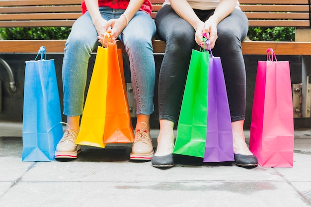 Free photo women sitting on bench with shopping bags