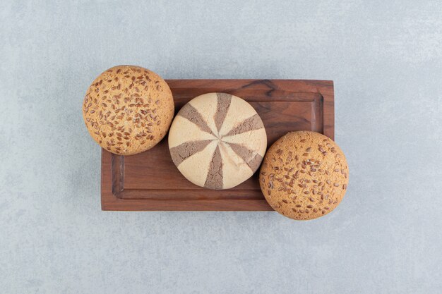 A wooden board full of sweet cookies . 