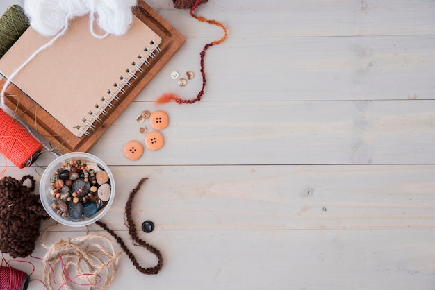 Wools; beads; string; spool on wooden desk