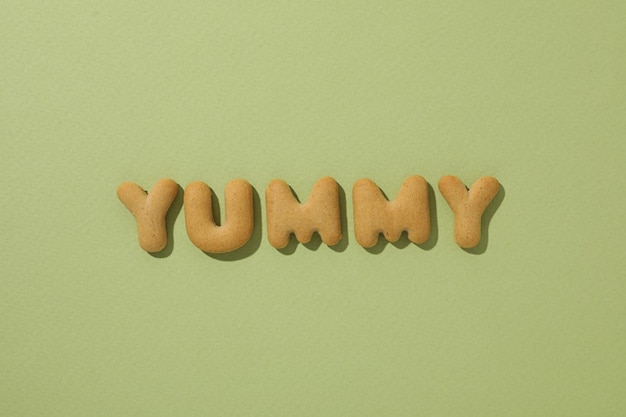 Free photo the word yummy laid out from cookies on a green background