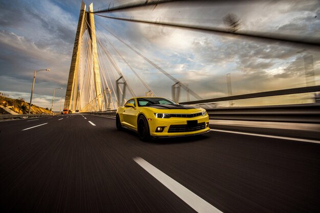 Yellow sport car with black autotuning on the bridge.