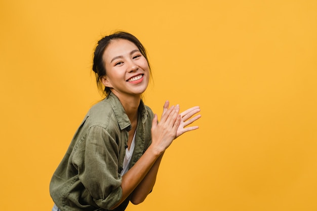 Free Photo young asian lady with positive expression, smile broadly, dressed in casual clothing  over yellow wall. happy adorable glad woman rejoices success. facial expression concept.