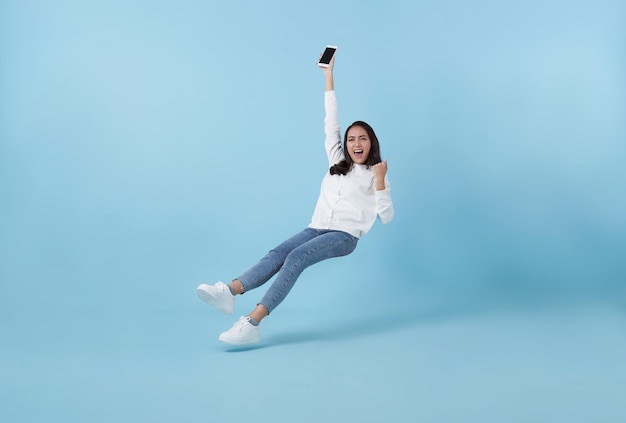 Free Photo young asian teenage girl happy hand holding mobile phone floating in midair isolated on blue background fast internet concept