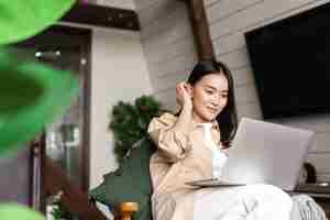 Free photo young asian woman sitting at home with laptop computer girl browsing websites or studying remotely