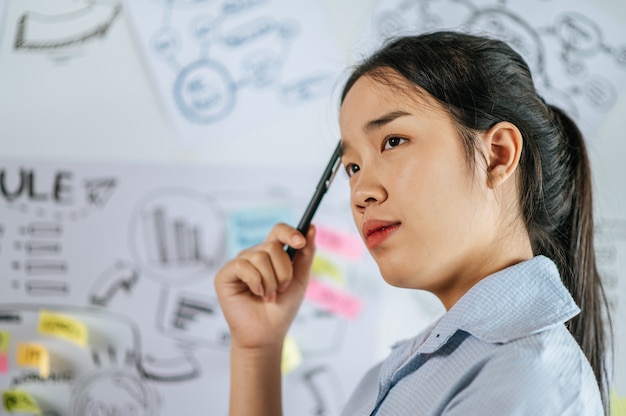 Free photo young asian woman standing and thoughtful how to present planing of project on board in meeting room, copy space