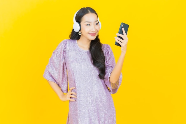 Free photo young asian woman with headphone and smart phone for listen music on yellow