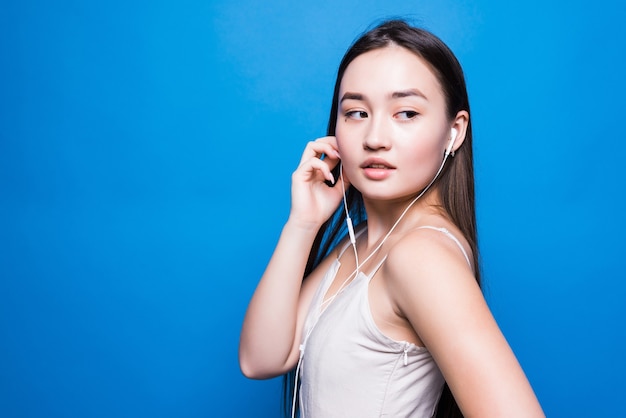 Free photo young attractive asian woman listening music on blue wall