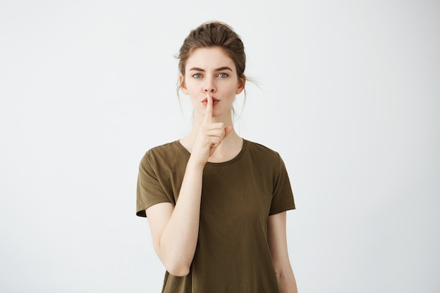 Free photo young beautiful brunette woman with bun showing keep silence.