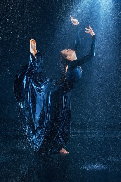 young beautiful modern dancer dancing under water drops